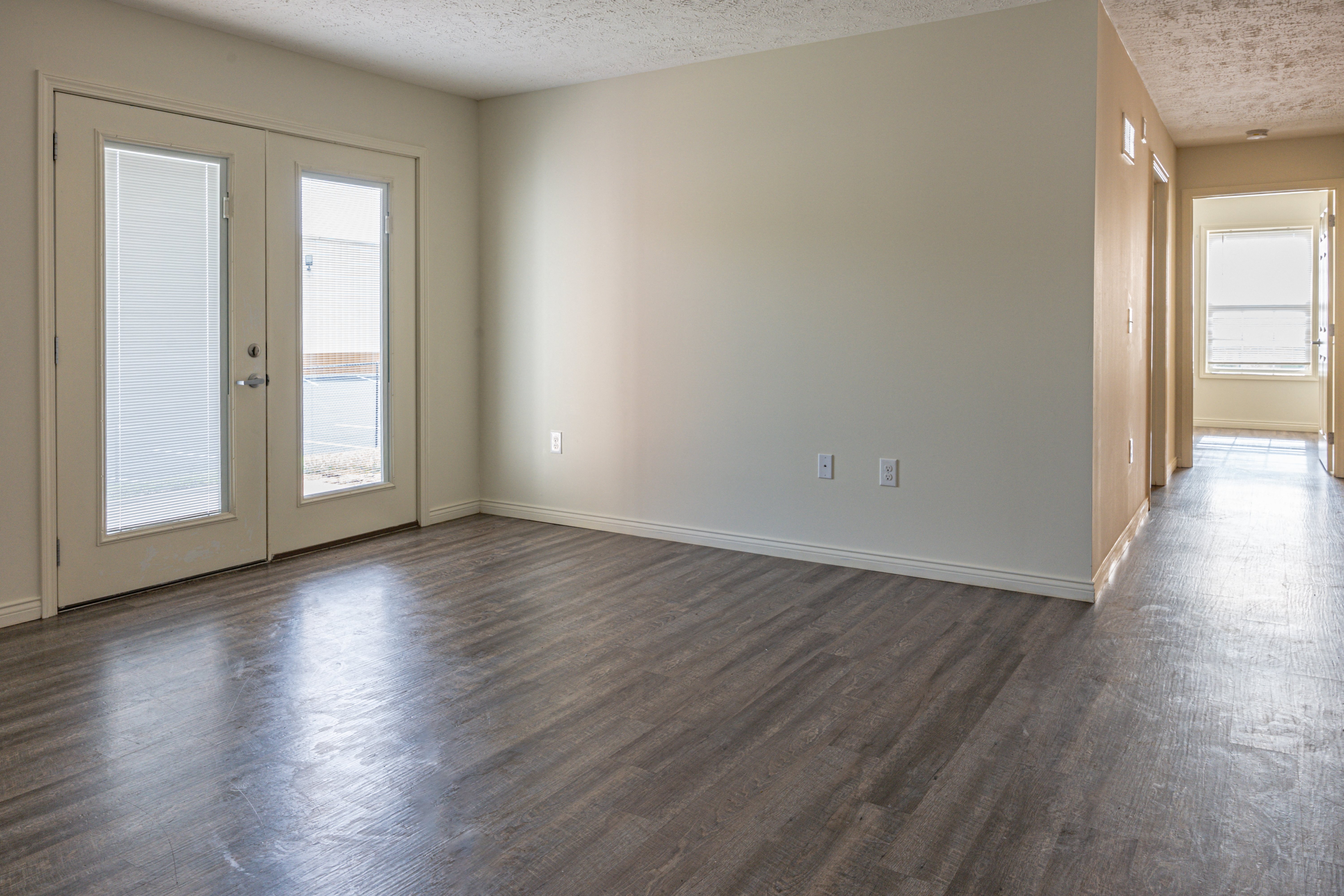 an empty living room with a hard wood floor and doors